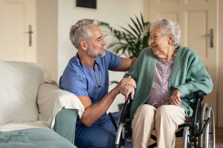 Older resident reviewing care documents with a family member at a dining table in an assisted living residence.